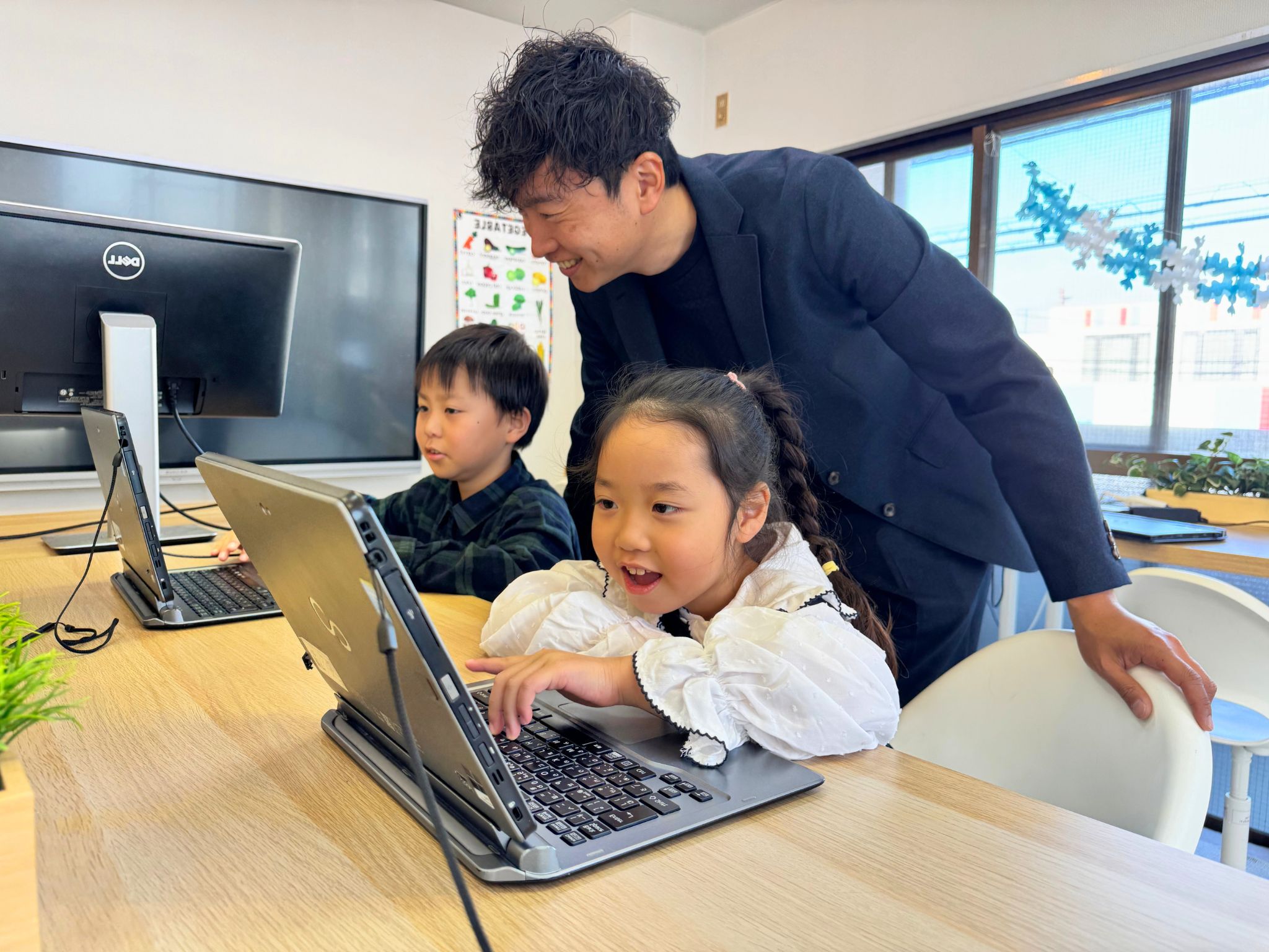 先生に見守られながら英語を学ぶ子どもたち